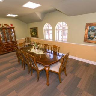 A well-appointed dining room featuring a large wooden table set with chairs, surrounded by decorative artwork and a display cabinet.