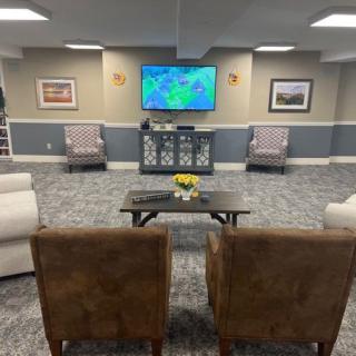 A cozy living room with a seating area and a wall-mounted television.