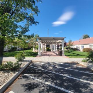 A sunny day view of a garden with a gazebo surrounded by trees and pathways.
