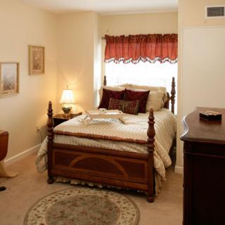 A cozy bedroom with a neatly made bed, a bedside lamp, and decorative elements.
