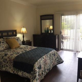 A cozy bedroom with a bed, dresser, and a window with curtains letting in natural light.