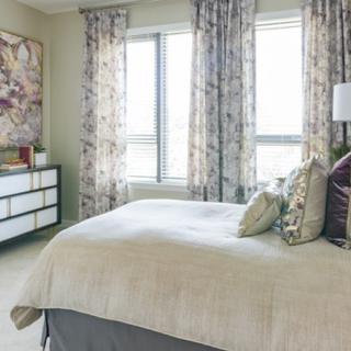 A well-decorated bedroom with a bed, dresser, and window with curtains.