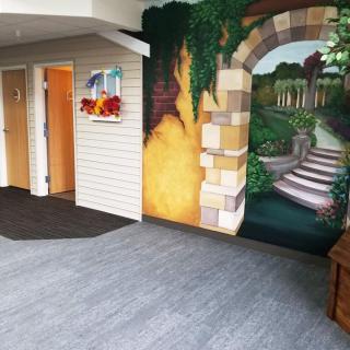 A beautifully painted mural depicting an archway and garden scene inside a building hallway.