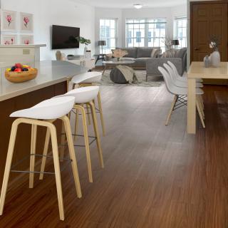 A modern open-plan kitchen and living room with sleek wood flooring and minimalist furniture.