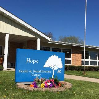 A sign for the Hope Health & Rehabilitation Center in front of a building with clear blue skies in the background.