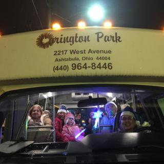 A lively group of people enjoying a night out on a decorated bus, illuminated by festive lights.