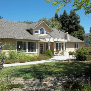 A beautiful single-story house surrounded by lush greenery and a well-maintained front yard.