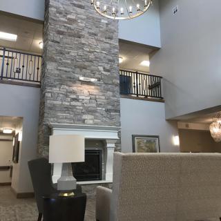 A modern lobby interior with a stone fireplace and chandelier.