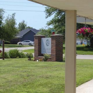 A neighborhood sign surrounded by grass and trees in a suburban area.