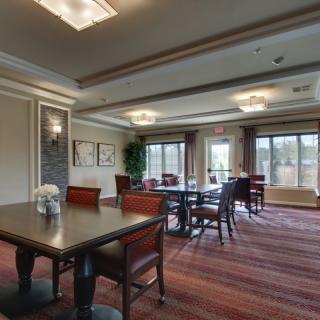 A well-lit conference room featuring multiple tables and chairs, with large windows providing natural light.