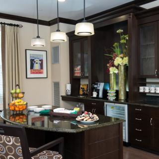 A modern kitchen with dark cabinets, an island counter, and stylish hanging lights.