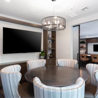 A modern conference room featuring a round table and a large screen, with minimalist decor and interior lighting.