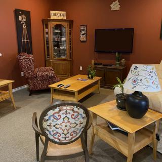 A cozy living room with various furniture pieces, including a coffee table, armchair, cabinet, and a TV.