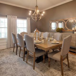 A beautifully decorated dining room with a large wooden table and elegant chairs beneath a chandelier.