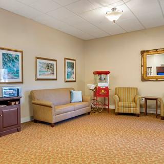 A cozy waiting room with comfortable seating, artwork on the walls, and a popcorn machine.