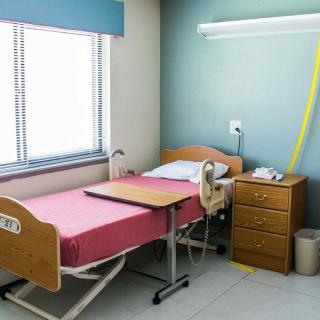 A clean and organized hospital room with a single bed and bedside table.