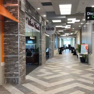 A view of a modern shopping mall corridor featuring various storefronts and contemporary design elements.
