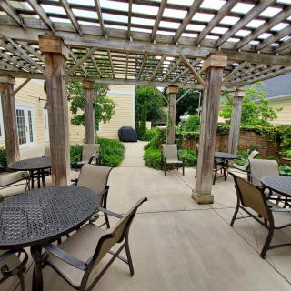 A beautiful outdoor patio area with a pergola, tables, and chairs, surrounded by lush garden landscaping.