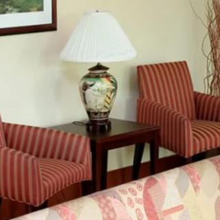 A cozy living room setup with two striped chairs and a decorative lamp on a small table.