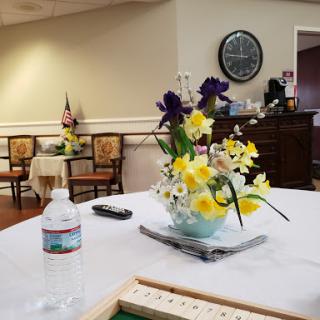 A cozy community room featuring a floral arrangement on the table and comfortable seating.