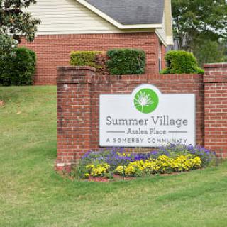 A brick sign for Summer Village, surrounded by landscaping and flowers.