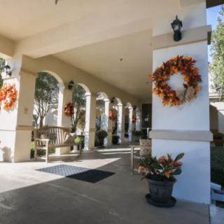 A porch decorated with autumn wreaths and plants, featuring a series of arches.