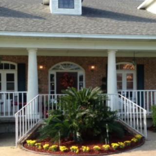 A welcoming porch with columns and well-maintained landscaping.