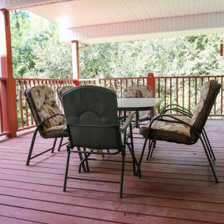 A cozy outdoor patio with a table and cushioned chairs on a covered deck.