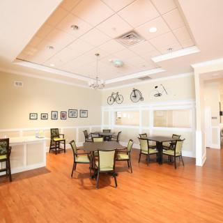 A bright and inviting dining area featuring multiple tables and chairs, warm wooden flooring, and decorative lighting.