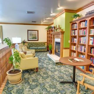 A cozy library corner with bookshelves, a fireplace, and comfortable seating.
