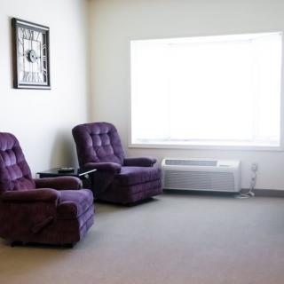 A cozy room with two purple chairs and a large window.