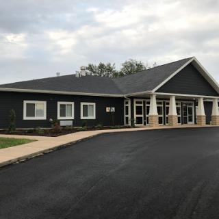 A modern commercial building with a dark exterior, surrounded by landscaped grounds.