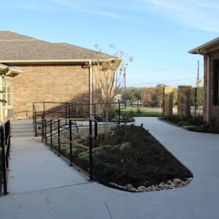 A well-designed outdoor space featuring a ramp for accessibility, surrounded by landscaping.