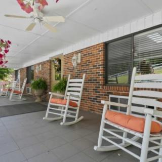 A peaceful porch with white rocking chairs and hanging plants.