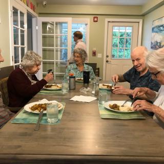 A group of elderly individuals enjoying a meal together at a dining table.