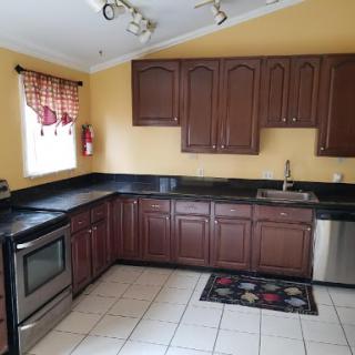 A well-lit kitchen featuring dark wood cabinets, stainless steel appliances, and a tiled floor.