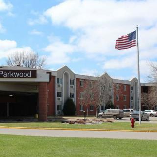 A hospital building with an American flag flying in front of its entrance on a cloudy day.