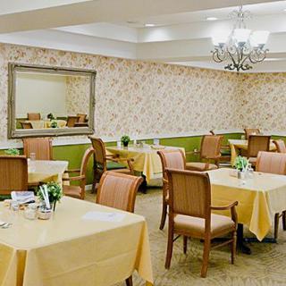 Elegant dining room with neatly arranged tables and chairs, decorated with a chandelier and wall mirror.