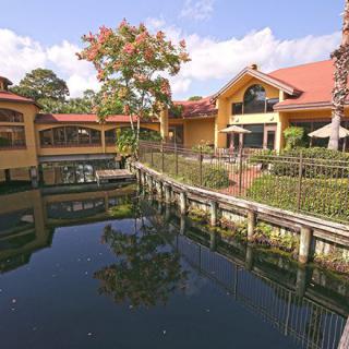 A scenic view of a building complex with a water feature and trees reflecting in the water.