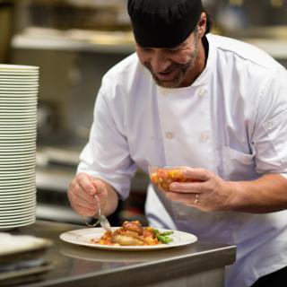 A chef carefully plating a dish in a professional kitchen.