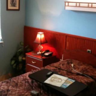 A cozy bedroom with a bed, nightstand, and lamp.