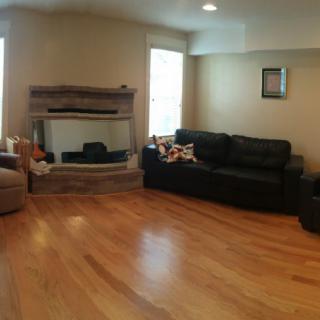 A cozy living room with a fireplace, two couches, and hardwood flooring.