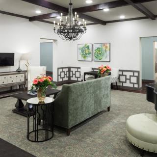 A modern living room with elegant decor, featuring a chandelier, green sofa, and stylish coffee tables.