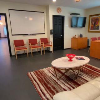 A cozy waiting room with chairs, a television, and a coffee table on a patterned rug.