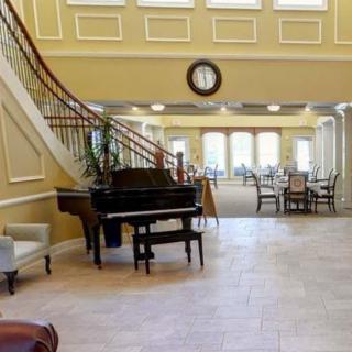 A spacious lobby featuring a grand piano and elegant staircase.