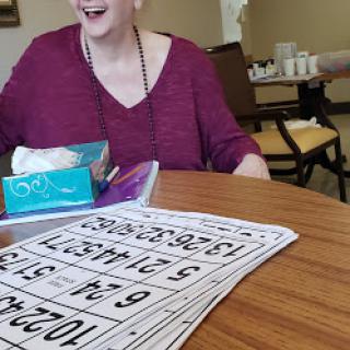 A cheerful senior woman enjoying a game of bingo with friends.