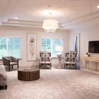 A modern living room with neutral tones, featuring comfortable seating, a central coffee table, and a chandelier.