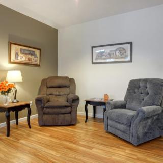A cozy living room with two plush armchairs, warm lighting, and decorative wall art.