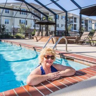 A woman enjoying a swim in an outdoor pool on a sunny day.
