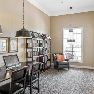 A modern home office with a desk, bookshelves, and a comfortable chair by the window.